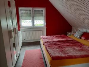 a red room with a bed and two windows at Ferienwohnung Sternfeld in Osburg