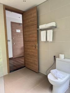 a bathroom with a toilet and a wooden door at Sky villa on the beach in Cat Ba