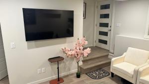 a living room with a tv and a chair and a tree at Comfy-home in YYC +10 photos