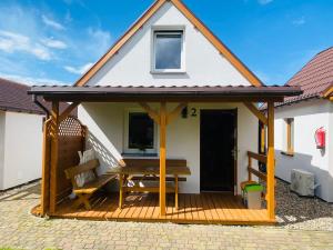a house with a wooden deck with a picnic table at DorJan - Domki Letniskowe in Dziwnówek