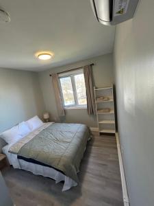 a small bedroom with a bed and a window at Modern Queen St Duplex 4BRs in Charlottetown