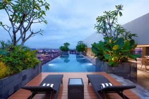 a swimming pool with two benches on a building at Oakwood Yogyakarta in Yogyakarta