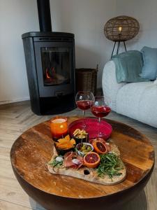 a table with wine glasses and food and a fireplace at Chez Firmin in Manhay