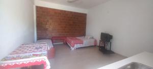 a room with two beds and a tv and a brick wall at Juaky market y alojamiento in Garupá