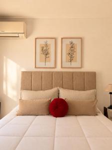 a large white bed with a red pillow on it at Cabañas Aires del Sur, con gran parque y pileta in Chascomús +22 photos