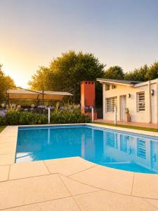 a swimming pool in front of a house at Cabañas Aires del Sur, con gran parque y pileta in Chascomús