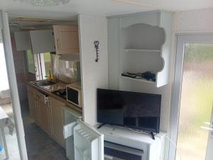 a kitchen with a tv and some cabinets and a counter at Camping les sumacs in Combles