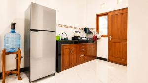 a kitchen with a stainless steel refrigerator and a bottle of water at Griya Mentari Homestay in Yogyakarta