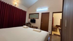 a bedroom with a white bed with two towels on it at Villa Bella in Ooty