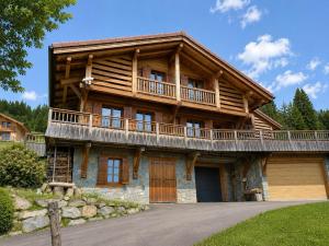 a large wooden house with a balcony at La Framboiseille - Chalet de Luxe avec Piscine Intérieure et Sauna - Vue Montagne in Manigod