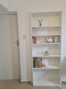 a white book shelf with books on it at Comfortable Secure Business Stay in Johannesburg