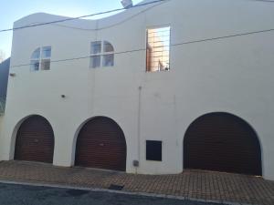 a white building with three brown garage doors at Comfortable Secure Business Stay in Johannesburg