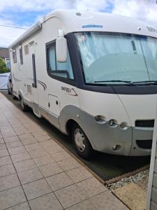 a white trailer parked next to a sidewalk at Chambre in Saint-Georges-du-Bois
