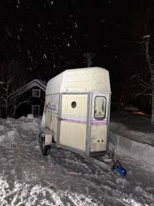 a small white trailer parked in the snow at Hytta Kilpisjärvi in Kilpisjärvi