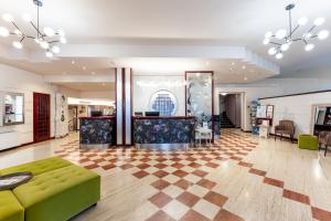 a lobby with a green couch and a checkerboard floor at Hotel Vittorio in Desenzano del Garda