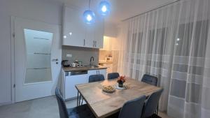 a kitchen with a table and chairs and a kitchen with white cabinets at Apartman Mešanović in Tuzla