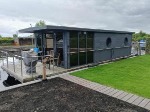 a tiny house on a dock on a body of water at Houseboat Enjoy with 200m Private Garden on the Lake in Vinkeveen