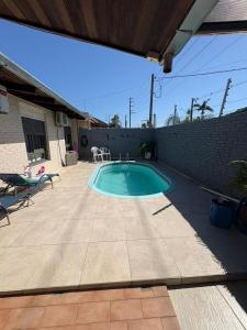 a swimming pool in a yard with a patio at Suíte aconchego dos pássaros in Guaratuba