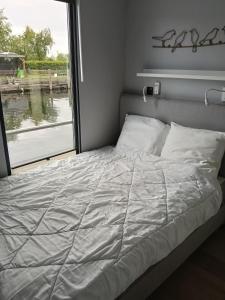 a bed in a room with a window at Houseboat Enjoy with 200m Private Garden on the Lake in Vinkeveen