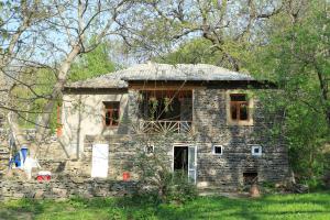 an old stone house in the middle of a field at Rahima's Guest House in Tadzhimi