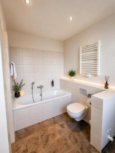 a white bathroom with a tub and a toilet at Hotel Pale Wolfsburg 24H Self Check-in in Wolfsburg +29 photos