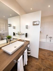 a bathroom with a large white sink and a tub at Hotel Pale Wolfsburg 24H Self Check-in in Wolfsburg