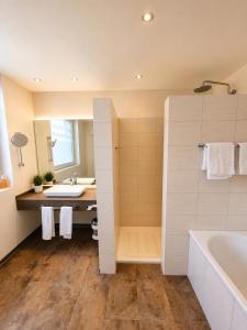 a bathroom with a bath tub and a sink at Hotel Pale Wolfsburg 24H Self Check-in in Wolfsburg