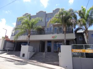 a building with palm trees in front of it at Enjoy 360 in Villa Carlos Paz