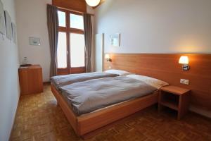 a bedroom with a large bed with a wooden headboard at Hotel Stüa Granda in Soglio