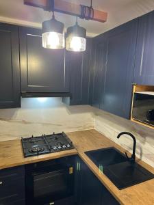 a kitchen with a stove and a sink and lights at Apartament Blue Velvet in Skierniewice +5 photos