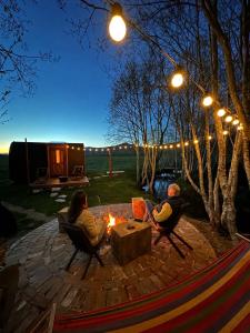 two people sitting around a fire pit at night at RAZBIBRIGA - Riverside Camping Pod by IGLENA in Kupres