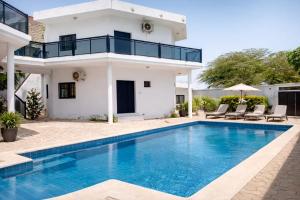 a villa with a swimming pool in front of a house at Izuba APPART' HÔTEL in Ngaparou