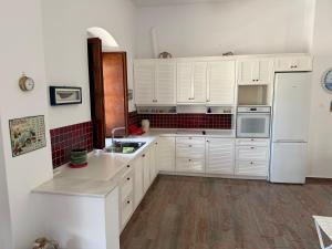 a kitchen with white cabinets and a white refrigerator at Villa Marco Polo in Agia Marina +19 photos