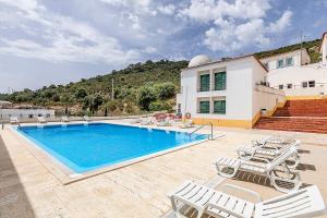 a swimming pool with chairs and a house at HI Alcoutim – Pousada de Juventude in Alcoutim