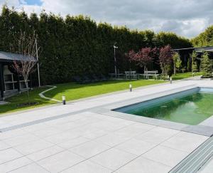 a swimming pool in front of a yard with trees at Apartamenty Lumax in Gryfice