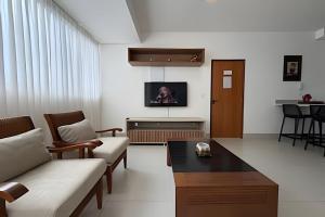 a living room with a couch and a tv on the wall at Aconchegante Apartamento com Ar Condicionado in Araxá