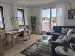 a living room with a blue couch and a table at Ferienwohnung mit Meerblick, 2 Schlafzi, Box- Bett, Süd- Balkon, eig, Parkplatz, Glasfaser in Dahme