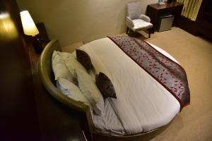 a bed in a hotel room with a white bedspread and pillows at Chola Nest in Ariyalūr