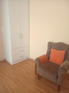 a chair with an orange pillow in a room at Buliso Homestay in Amsterdamhoek
