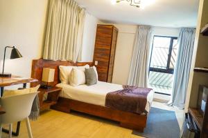 a bedroom with a bed and a desk and a window at Distrito 27 in Santo Domingo