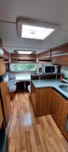 a kitchen in an rv with a sink and a table at Gezellige luxe caravan met zwembad in zuid- Bourgogne in Anglure-sous-Dun
