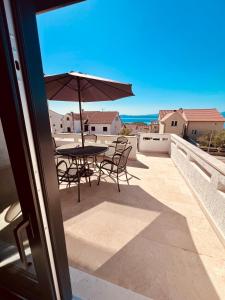 a patio with a table and chairs and an umbrella at Casa Milano Krk in Njivice