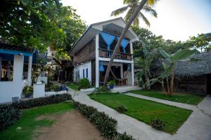 a house with a palm tree in front of it at Surf Resort Arugambay in Arugam Bay