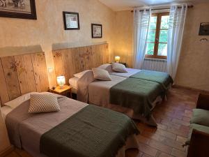 a hotel room with two beds and a window at Le Degoutaud in Le Barroux