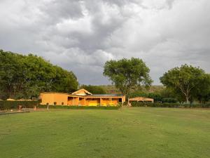 a house in the middle of a green field at Drona Farms in Bhundsi