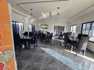 a dining room with black tables and chairs and windows at Chaniche Executive Lodge in Ndola