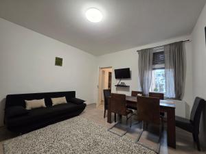 a living room with a couch and a dining room table at Smeraldo Home Fsz in Siófok