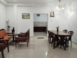 a dining room with tables and chairs and a kitchen at Jayasiri Riverfront Home in Lansiyawatta