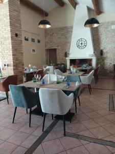 a restaurant with tables and chairs and a clock on the wall at Logis Hôtel Restaurant La Bastide Saint Bach in Suze-la-Rousse