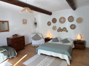 a bedroom with two beds and a chair and mirrors at Le Degoutaud in Le Barroux